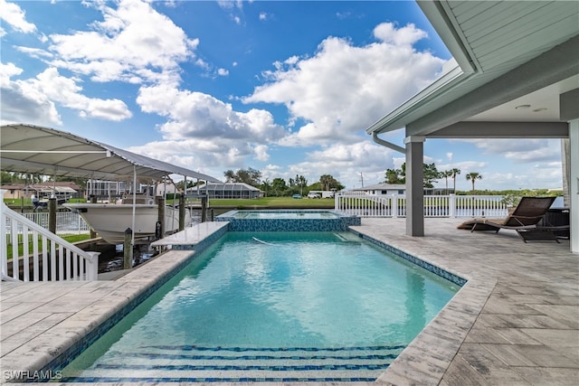 view of pool with an in ground hot tub, a water view, a dock, and a patio area