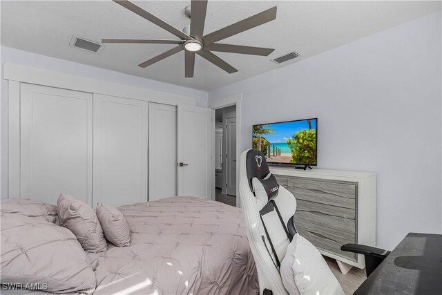 bedroom with ceiling fan, a closet, a textured ceiling, and hardwood / wood-style flooring