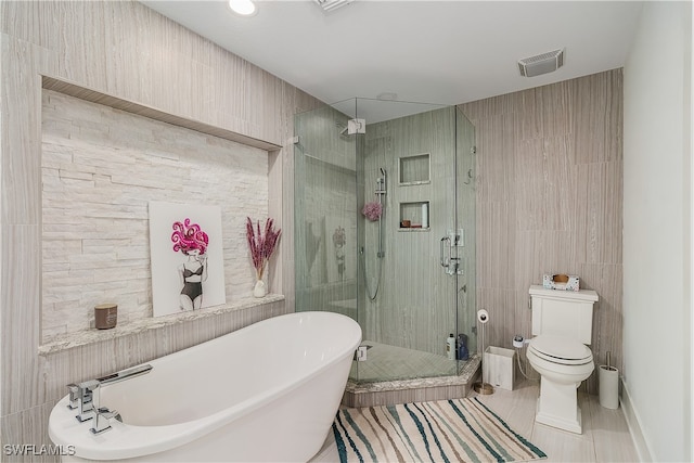 bathroom with toilet, tile patterned floors, separate shower and tub, and tile walls