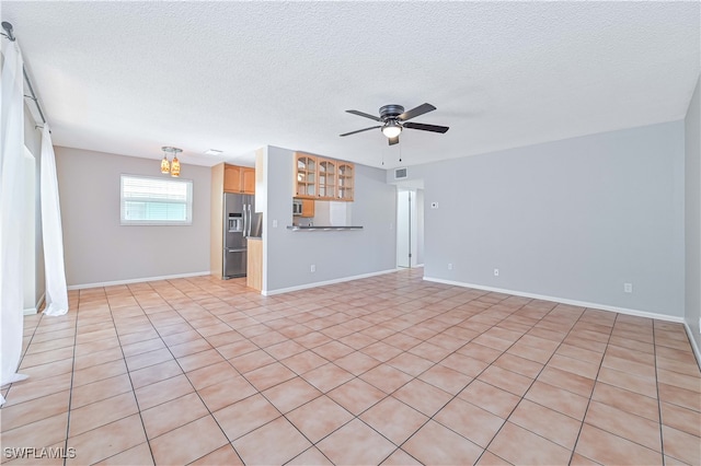 unfurnished living room featuring a textured ceiling, ceiling fan, and light tile patterned flooring