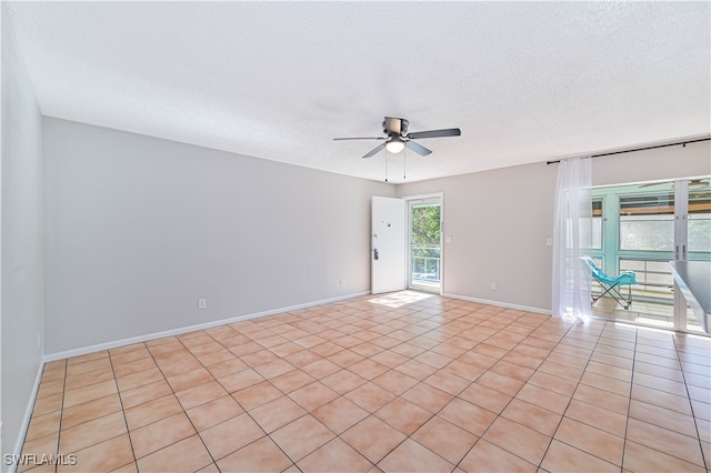 empty room with ceiling fan, light tile patterned floors, and a textured ceiling