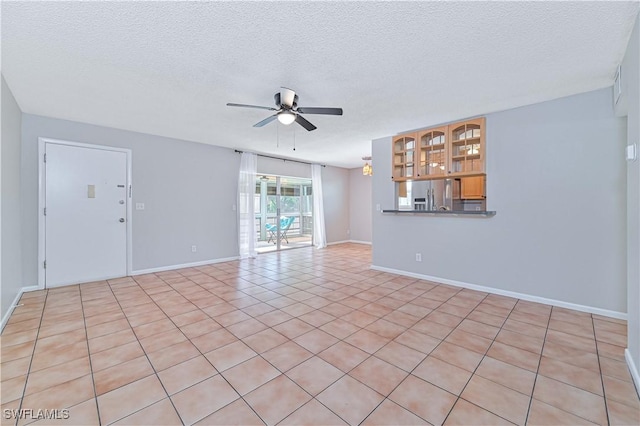 unfurnished living room with ceiling fan, light tile patterned floors, and a textured ceiling