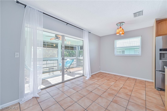 unfurnished dining area featuring a textured ceiling, ceiling fan, and light tile patterned flooring