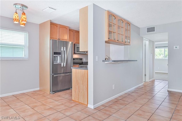 kitchen featuring stainless steel appliances, light tile patterned flooring, pendant lighting, and a textured ceiling