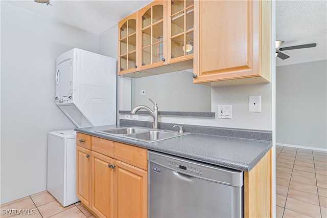 kitchen featuring stacked washer and dryer, sink, stainless steel dishwasher, ceiling fan, and light tile patterned floors