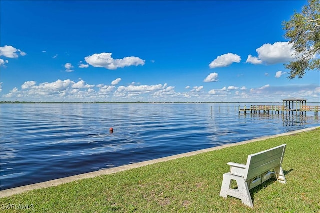 dock area with a water view and a lawn