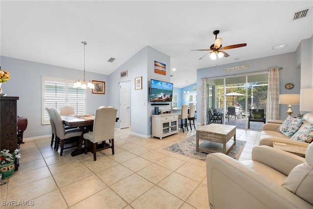 tiled living room featuring ceiling fan with notable chandelier, vaulted ceiling, and plenty of natural light