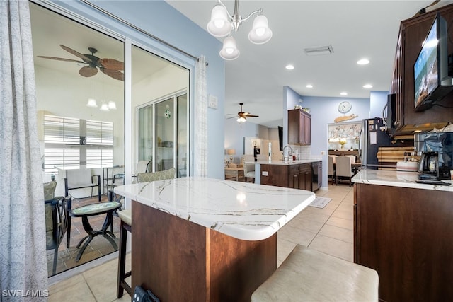 kitchen with sink, kitchen peninsula, decorative light fixtures, a breakfast bar, and light tile patterned floors