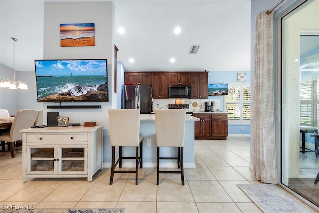 kitchen with a kitchen bar, stainless steel refrigerator with ice dispenser, stove, decorative light fixtures, and a notable chandelier