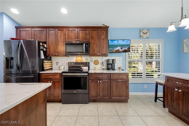 kitchen with light tile patterned floors, tasteful backsplash, decorative light fixtures, light stone counters, and stainless steel appliances