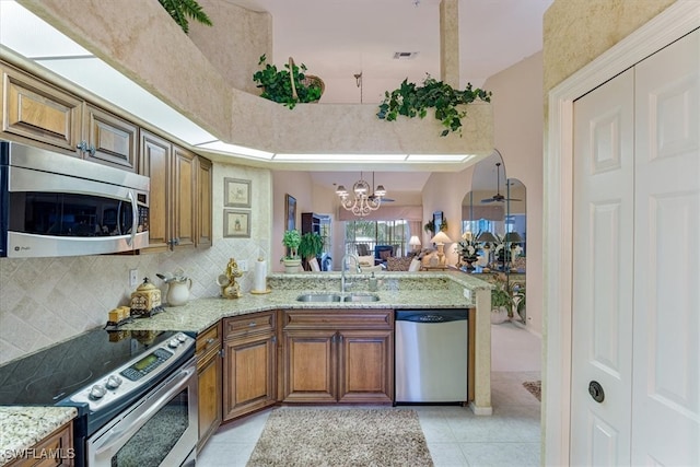 kitchen with an inviting chandelier, sink, light tile patterned floors, appliances with stainless steel finishes, and kitchen peninsula