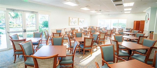 dining space featuring a paneled ceiling, ceiling fan, french doors, and a healthy amount of sunlight