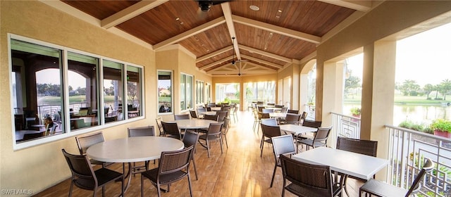 sunroom with lofted ceiling with beams, a water view, and wooden ceiling