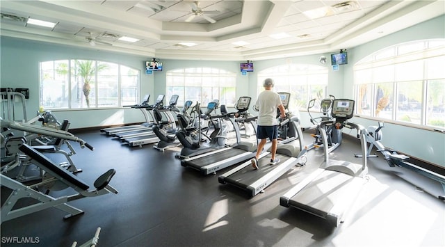 exercise room featuring ceiling fan, visible vents, and a tray ceiling