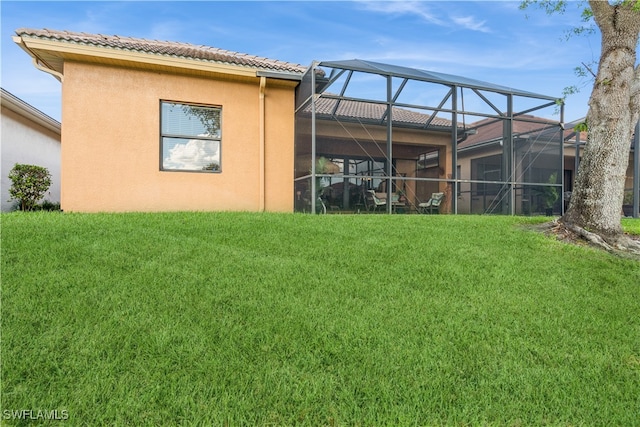 rear view of house featuring a lanai and a lawn