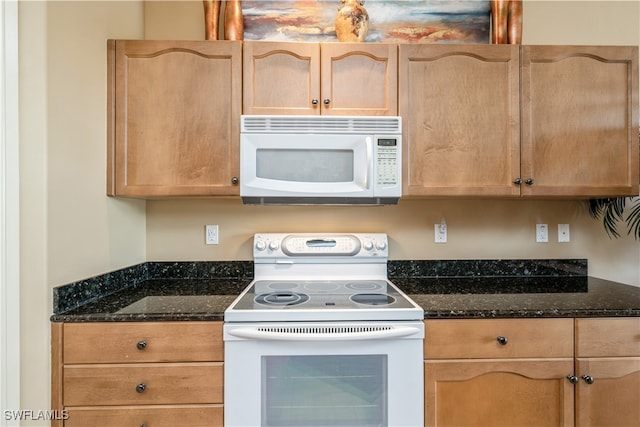 kitchen featuring dark stone countertops and white appliances