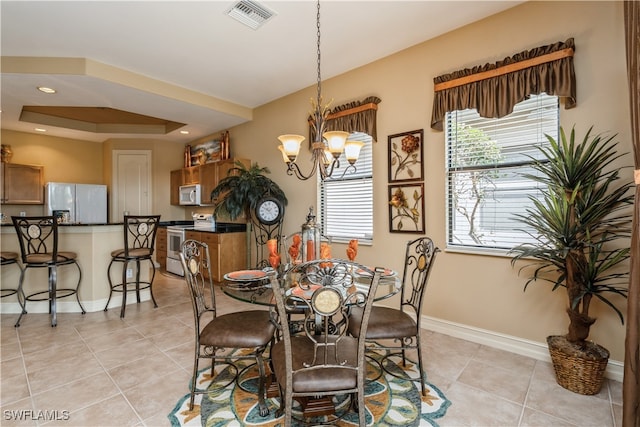 dining area featuring a chandelier, light tile patterned floors, and a raised ceiling