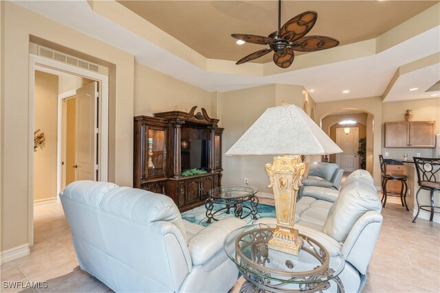 living room featuring ceiling fan, light tile patterned flooring, and a raised ceiling