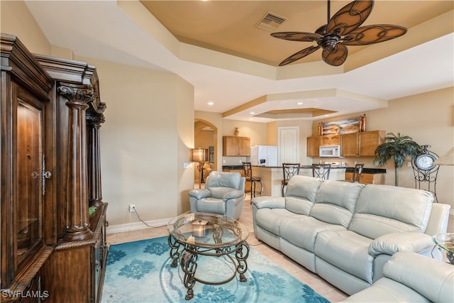 living room featuring a tray ceiling, ceiling fan, and light tile patterned flooring