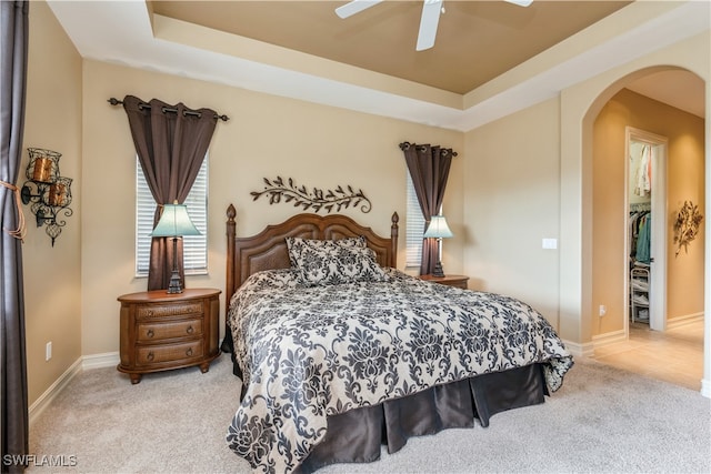 carpeted bedroom with a closet, a raised ceiling, and ceiling fan