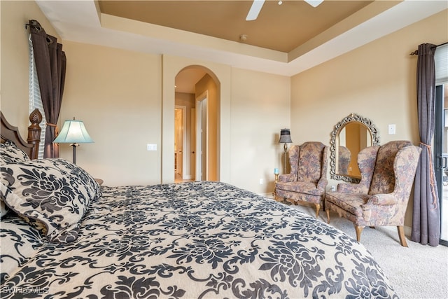 carpeted bedroom with a tray ceiling and ceiling fan