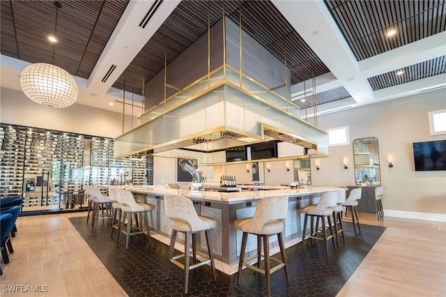 kitchen featuring wood-type flooring, a towering ceiling, hanging light fixtures, and a breakfast bar area