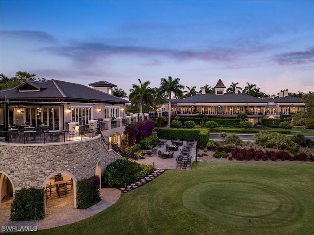 5100 Baybridge Blvd Unit 1901, Estero, FL 33928 - back of property at dusk with a patio area, a lawn, and stone siding