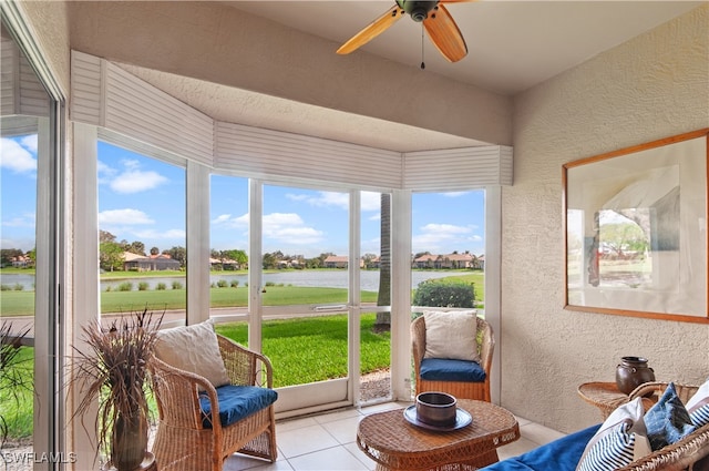 sunroom / solarium featuring a water view, plenty of natural light, and ceiling fan