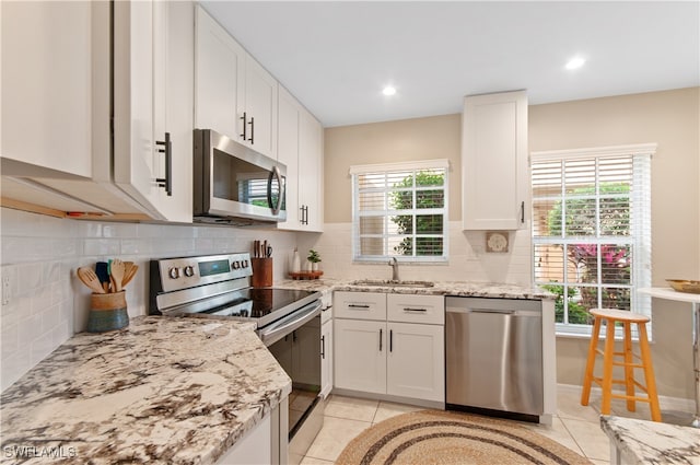 kitchen featuring white cabinetry, sink, light tile patterned flooring, and stainless steel appliances