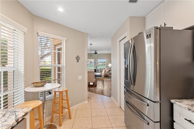 kitchen featuring stainless steel fridge, light stone counters, ceiling fan, light hardwood / wood-style flooring, and white cabinets