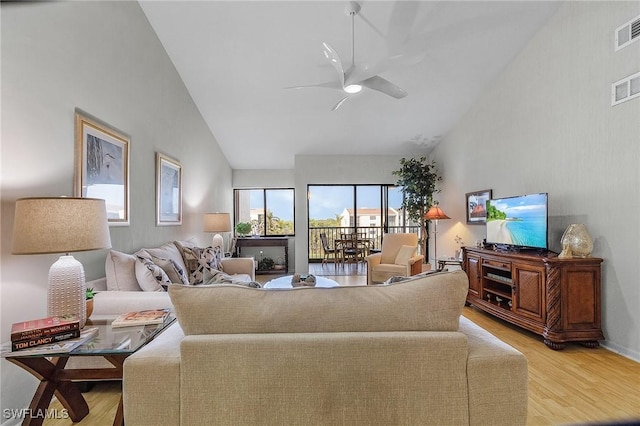 living room featuring ceiling fan, vaulted ceiling, and light wood-type flooring