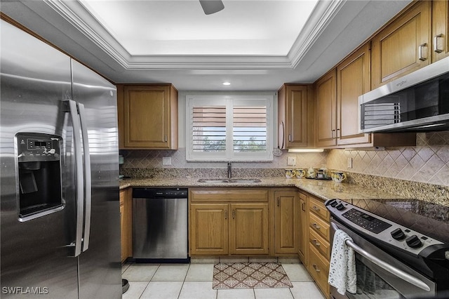 kitchen featuring a raised ceiling, stainless steel appliances, light stone counters, and sink