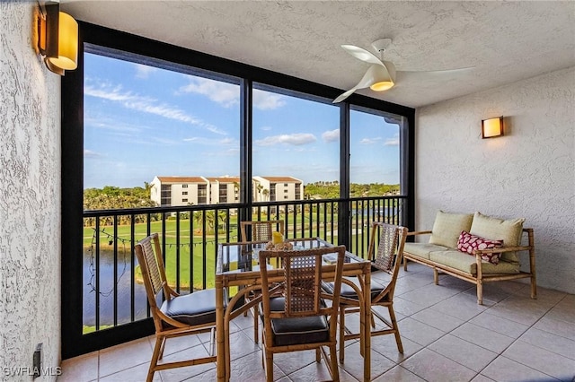 sunroom / solarium with ceiling fan and a water view