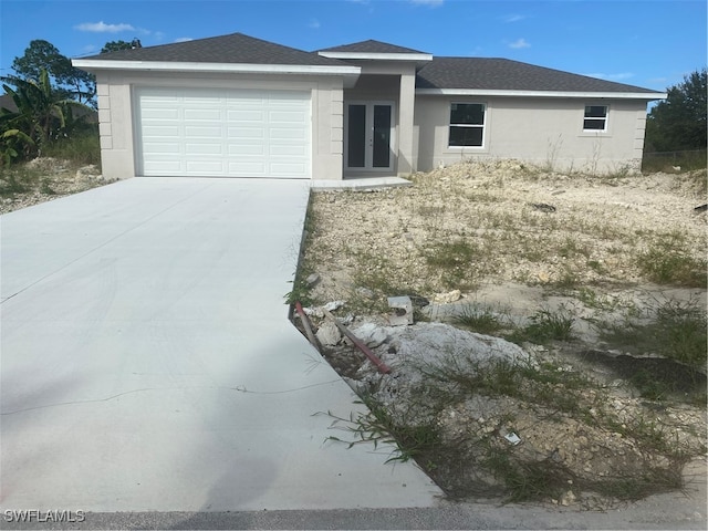 view of front of property featuring stucco siding, french doors, an attached garage, and driveway