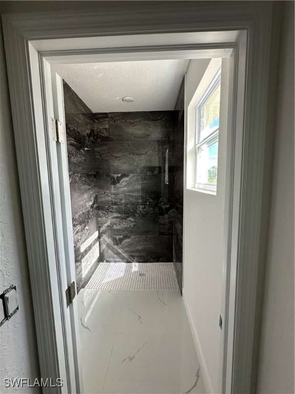 bathroom featuring a tile shower and a textured ceiling