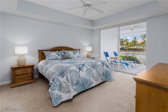 bedroom with light colored carpet, a ceiling fan, baseboards, access to outside, and a tray ceiling