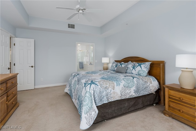 bedroom featuring light colored carpet, baseboards, visible vents, and a tray ceiling