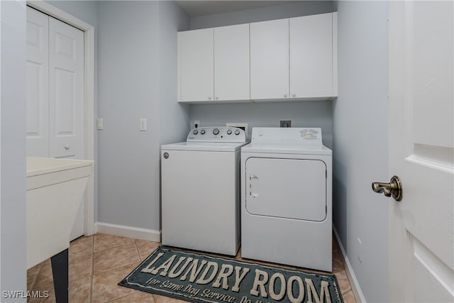 laundry area with baseboards, cabinet space, washing machine and clothes dryer, and light tile patterned floors