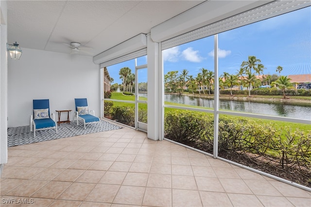 unfurnished sunroom featuring ceiling fan and a water view