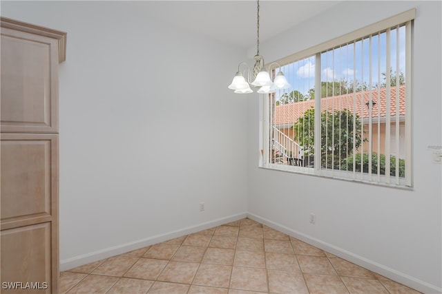 unfurnished dining area featuring a notable chandelier, baseboards, and light tile patterned floors