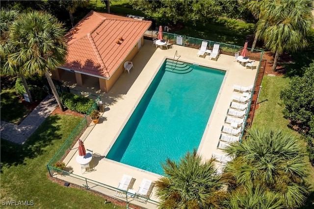 community pool with a patio area and fence