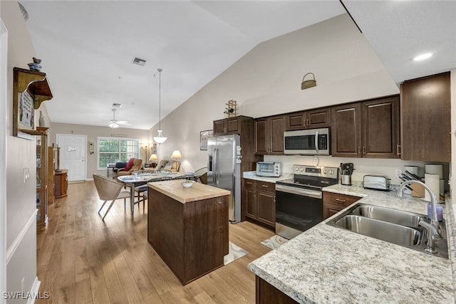 kitchen featuring sink, a center island, vaulted ceiling, appliances with stainless steel finishes, and light wood-type flooring