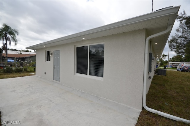 view of side of property with central AC unit, a patio, and a lawn