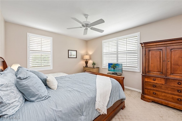 bedroom featuring ceiling fan, multiple windows, and light colored carpet