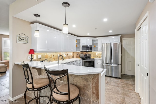 kitchen with kitchen peninsula, stainless steel appliances, white cabinets, and hanging light fixtures