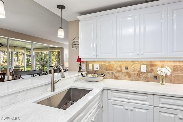 760 Waterford Dr Unit 104, Naples, FL 34113 - kitchen featuring decorative backsplash, hanging light fixtures, a sink, light stone counters, and white cabinets