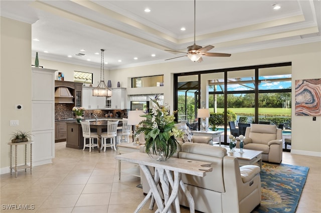 tiled living room with ceiling fan, a raised ceiling, and crown molding