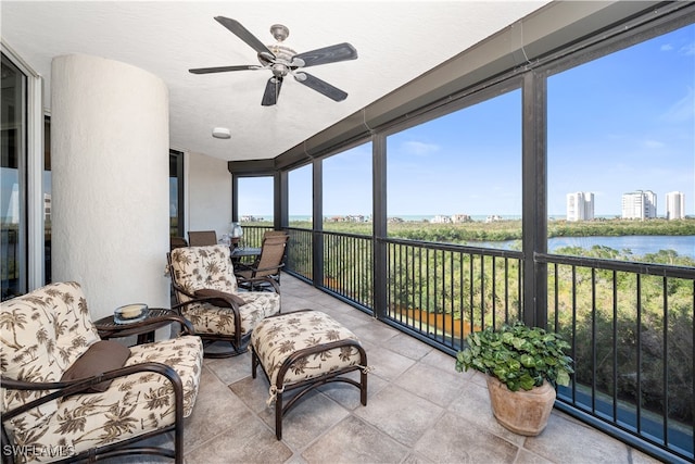 sunroom / solarium featuring ceiling fan and a water view