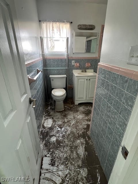 bathroom with vanity, toilet, and tile walls