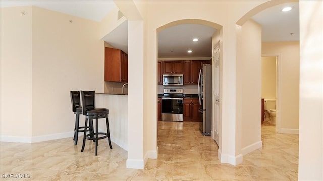 kitchen featuring baseboards, recessed lighting, appliances with stainless steel finishes, arched walkways, and marble finish floor